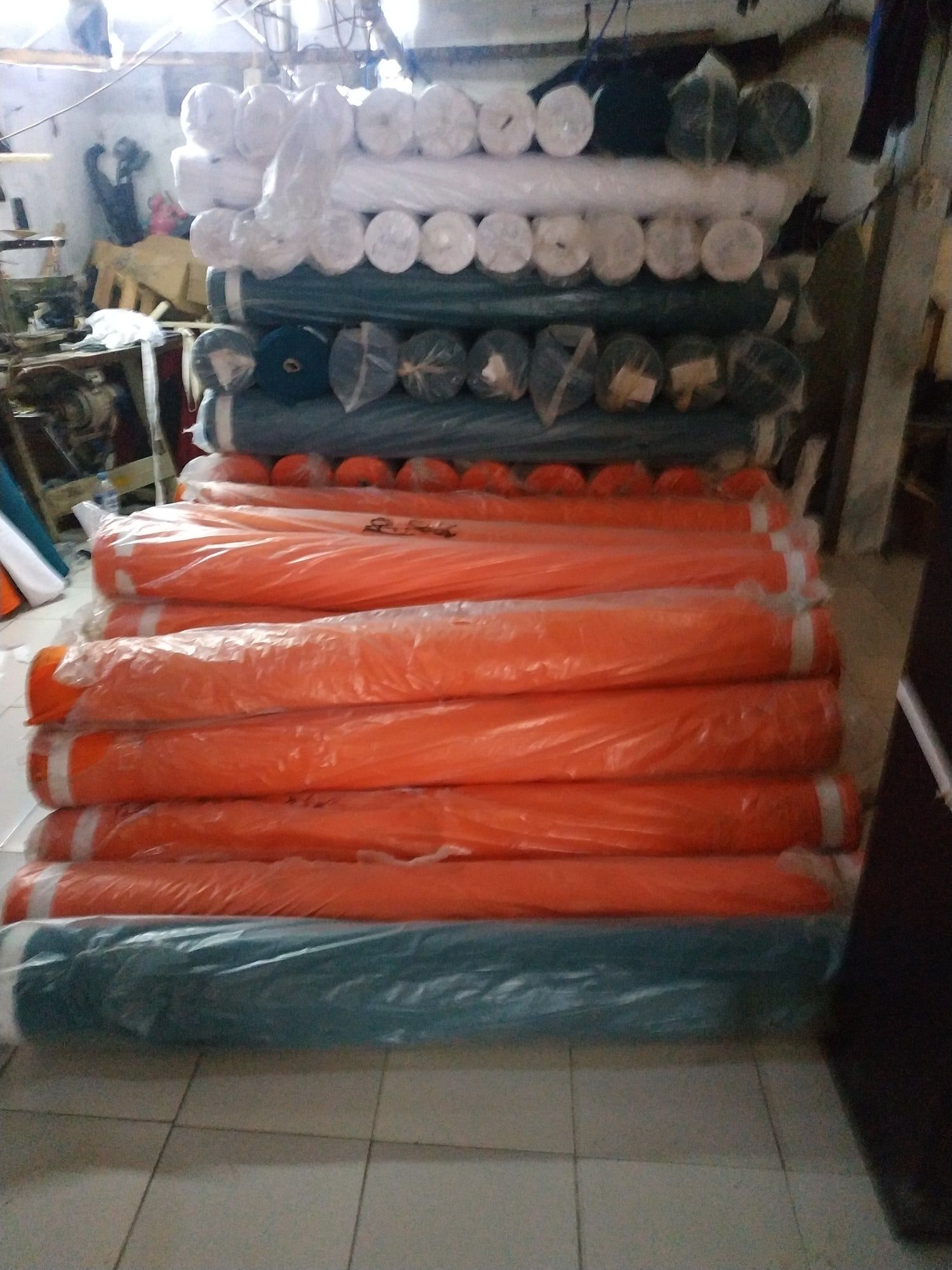 Gulungan kain oranye dan hijau tua di gudang bahan